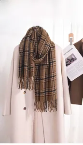 Detail eines braun karierten Schals mit Fransen auf einem beigen Wollmantel