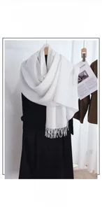 Close-up of soft white cashmere-like scarf with long fringe tassels for winter warmth