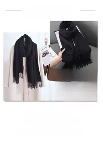 Close-up of thick black cashmere scarf texture and fringe detail on beige wool coat