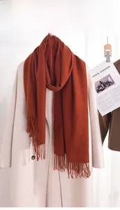 Detail of soft caramel red cashmere-feel scarf featuring thick texture and fringe tassels