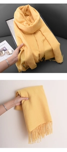 Detail of bright yellow cashmere-feel scarf with fringes on a sofa and hand-held view