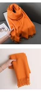 Detail of bright orange cashmere shawl featuring thick texture and elegant long tassels
