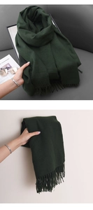 Close-up of soft dark green cashmere-feel scarf featuring dense fringe tassels and texture