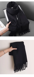 Close-up detail showing the fine texture and fringe of the black cashmere-like scarf