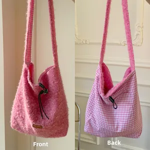 Detail of pink faux fur and plaid fabric textures on a versatile reversible crossbody bag