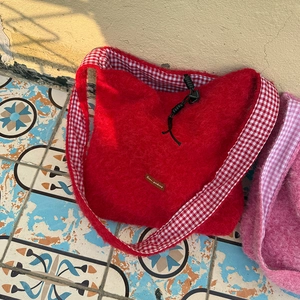 Close-up of red fuzzy tote bag showing plush texture and gingham drawstring lining