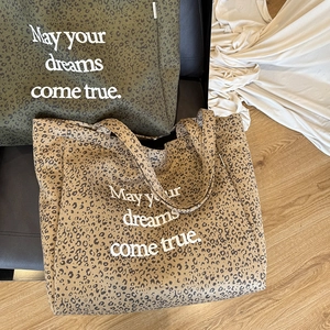 Detail of leopard print suede tote bags in olive green and khaki with slogan print
