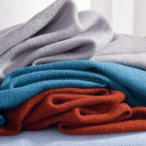 Soft cashmere-like winter scarf in grey, peacock blue and orange colors with knit texture