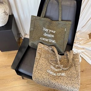 Close-up of leopard print suede tote bags with white inspirational quote print