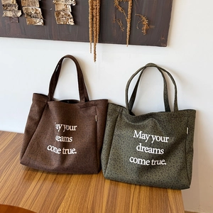 Detail of leopard print suede tote bags in brown and green with dream quote