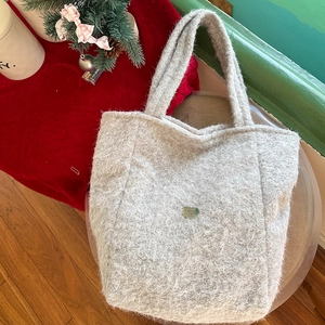 Détail du sac fourre-tout en peluche grise avec logo métallique et texture mohair douce