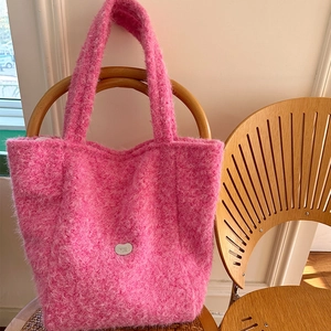 Gros plan sur le sac fourre-tout rose en peluche avec un petit logo en métal argenté