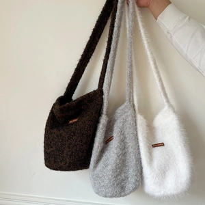 Detailed view of plush faux fur tote bags in brown, grey, and white with leather labels