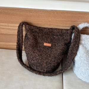 Detail of plush bucket bag featuring brown knit texture and orange Star-picking leather tag