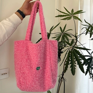 Détail de la texture d'un sac cabas en peluche rose avec badge cœur vert