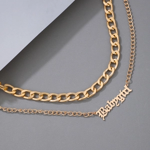 Details einer mehrlagigen goldenen Panzerkette mit Babygirl-Buchstabenanhänger