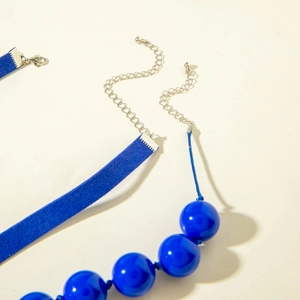 Exaggerated large blue beaded necklace set with velvet strap and heart pendant detail