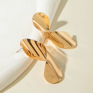Détail de boucles d'oreilles feuilles dorées polies avec design ondulé et ombres portées