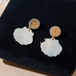 Detail of gold shell drop earrings with pearl luster on a black velvet display background