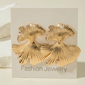 Boucles d'oreilles dorées en forme d'éventail sur carte bijoux et pierre décorative