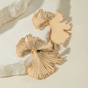 Vue détaillée des boucles d'oreilles feuilles de ginkgo dorées sur pierre