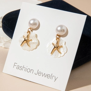 Bohemian seashell and pearl drop earrings featuring golden starfish on display card
