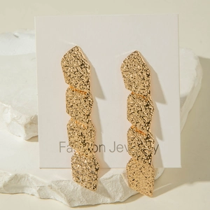 Détail de boucles d'oreilles feuilles dorées avec texture martelée sur présentoir