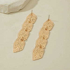 Détails de boucles d'oreilles pendantes dorées avec texture martelée et hexagones