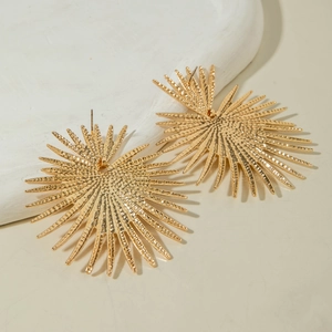 Vue détaillée de boucles d'oreilles dorées en forme de soleil sur support en pierre