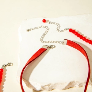 Détail du ras de cou cœur rouge et collier de perles avec fermoir argenté sur pierre