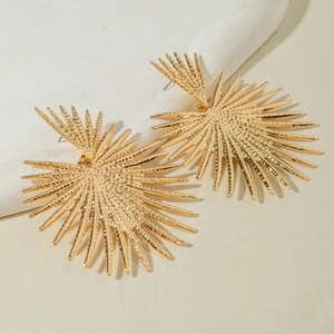 Détail de grandes boucles d'oreilles dorées avec texture martelée et éclat métallique