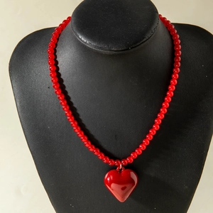 Détail du pendentif cœur rouge vif en acrylique et collier de perles style cerise