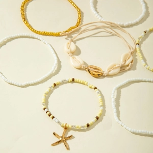 Summer beach shell and gold bead 6-piece anklet set with starfish pendant on cream background