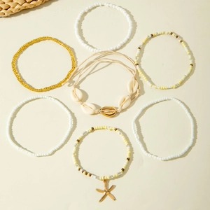Detail of 7-piece bohemian anklet set featuring seed beads and natural cowrie shells