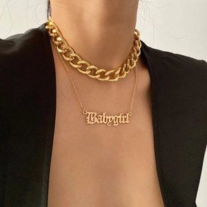 Lagen-Halskette in Gold mit Babygirl-Anhänger im Gothic-Stil auf einem schwarzen Anzug