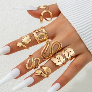 Golden stackable ring set featuring geometric floral leaf and hugging hand designs