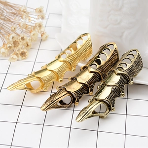 Close-up of gothic punk long claw rings in gold and bronze finish on textured surface