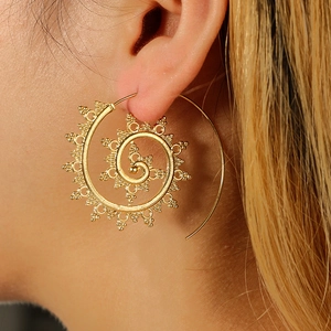 Detailed view of bohemian style golden spiral hoop earrings worn by a model