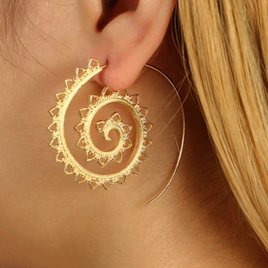 Close-up of bohemian gold spiral teardrop earring with intricate hollow patterns