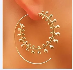 Detail of gold spiral drop earring with textured beads on a model's ear