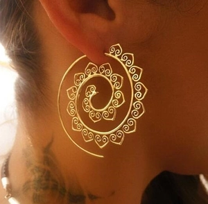 Detail of gold spiral hoop earrings with heart cutouts worn on a model's ear