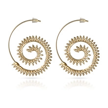 Detail of golden spiral leaf earrings with serrated edges and bohemian retro style
