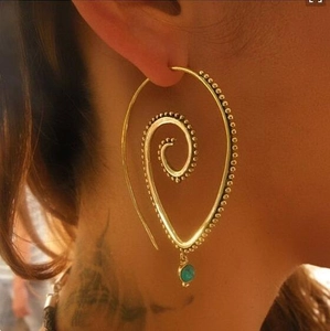 Macro detail of golden spiral earrings with beaded edges and turquoise pendant drop