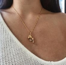Detailed close-up of a delicate gold rose pendant necklace on a model clavicle