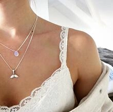 Detail of layered silver necklace with lavender stone and whale tail pendant on a model