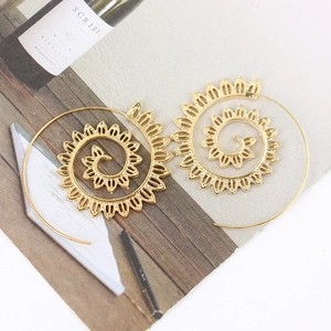 Macro detail of golden spiral leaf earrings with sunburst texture on a rustic background