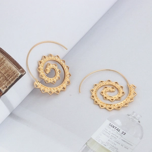 Close-up of golden oval spiral earrings featuring intricate hollow carved details