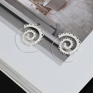 Detailed view of silver mandala hollow spiral earrings on a minimalist magazine background