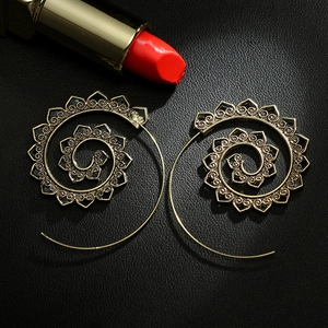 Detail of vintage gold spiral earrings with hollow floral textures on black leather background