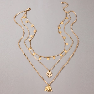 Detail of gold multilayered necklace with elephant and monstera leaf pendants